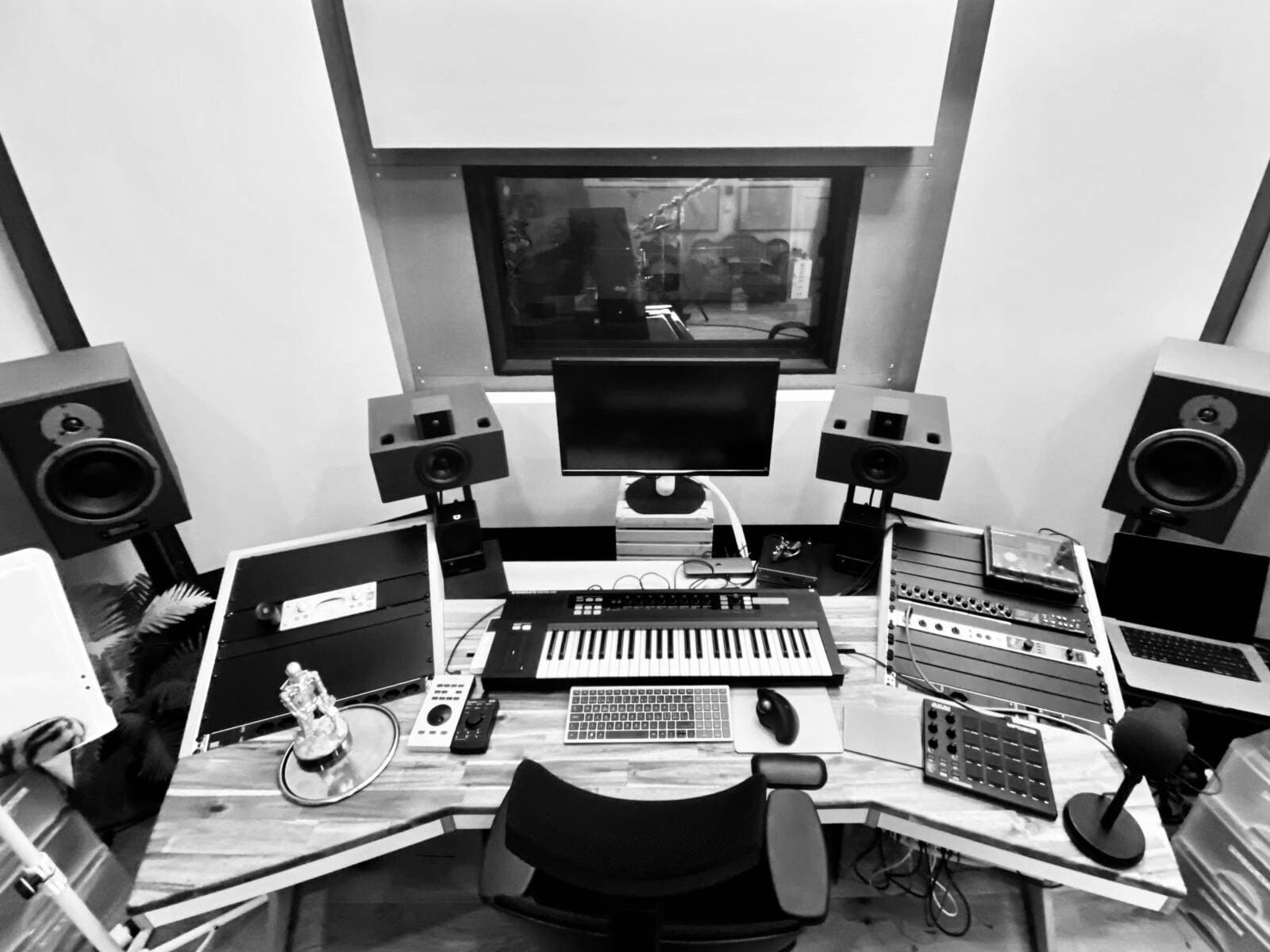 The Jungle producer desk with studio monitors, a MIDI keyboard, outboard gear and the window into the live room