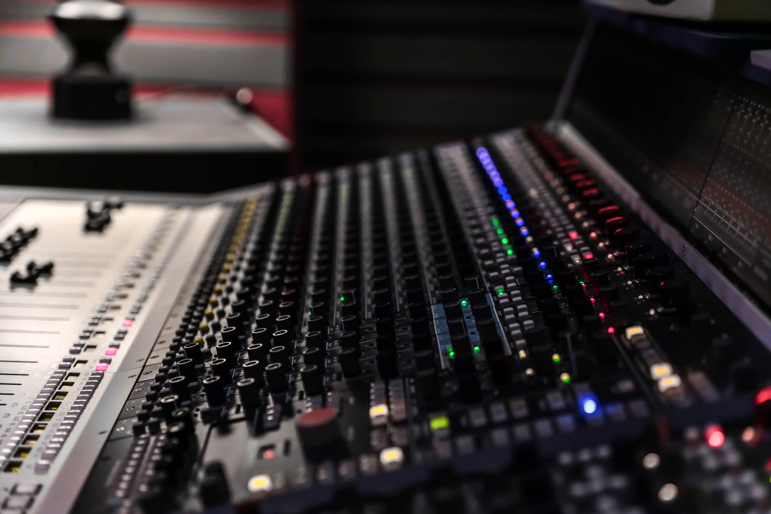 Close-up of the Suite console faders and channel LEDs, with the striped acoustic wall behind